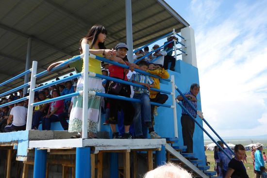 Zuschauer verfolgen das Pferderennen von der Tribüne aus ...