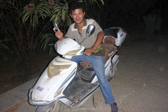 Madar grüßt zum Abschied auf seinem Elektroroller