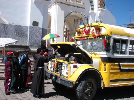 Der Priester segnet den geschmueckten Schulbus.