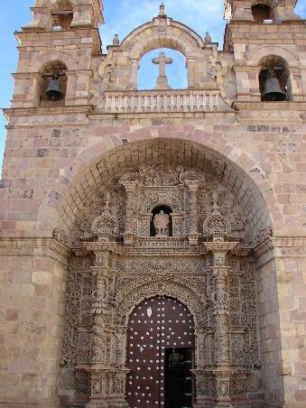 Die Iglesia San Lorenzo beeindruckt mit einem Portal, das im typischen Estilo Mestizo gestaltet ist. Die indigenen Kuenstler haben ihre wichtigsten Symbole wie Sonne und Mond, Planzen und Gesichter mit eingearbetet.