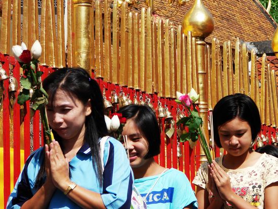 Glaeubige Thais ziehen mit Lotusblueten um den innersten Bereich des Tempels.