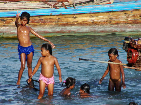 Kinder benutzen die Boote und das Meer als Spielplatz.