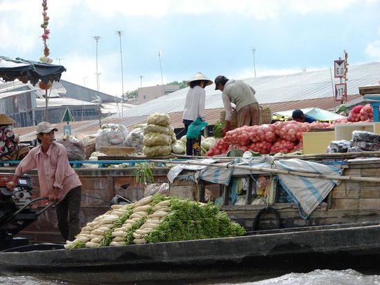 Die Grosshaendler verkaufen die Gueter an die Detailhaendler auf ihren kleinen Booten.