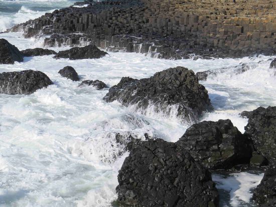 Gischt über schwarzen Blöcken