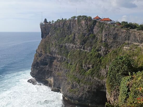 Vorn auf der Klippe der kleine aber auf Bali bedeutsame Uluwatu-Tempel.