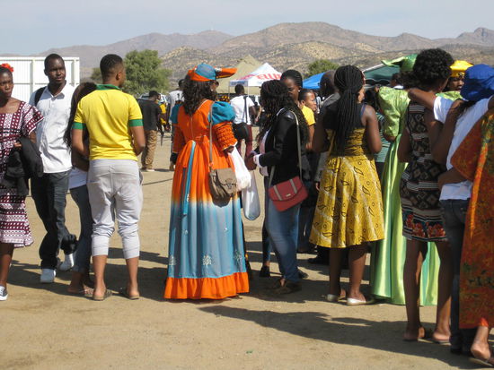 Einige der Mädels tragen die traditionellen Hererokleider. Allerdings nicht in den eher langweiligen und biederen Farben sondern mit fließenden modernen Stoffen und in sehr bunten Farben (wie hier in orange-blau und in glänzendem hellgrün).