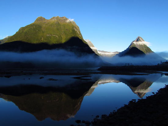 Am frühen Morgen spiegelt sich der Mitre Peak im stillen Wasser des Sounds.