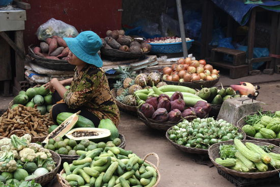 Marktfrau inmitten von Gemüse