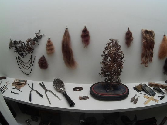 Die Haarbürste in diesem Fenster ist in Wirklichkeit ein Föhn, man füllte heißes Wasser über den Griff in den Kopf und bürstete dann damit das nasse Haar