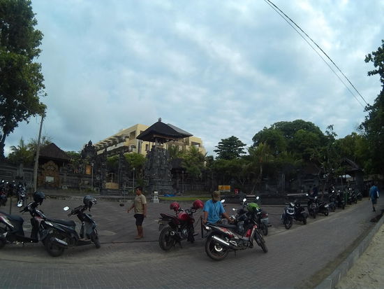 Roller parken am Strand, dahinter ein Tempel und Hotels