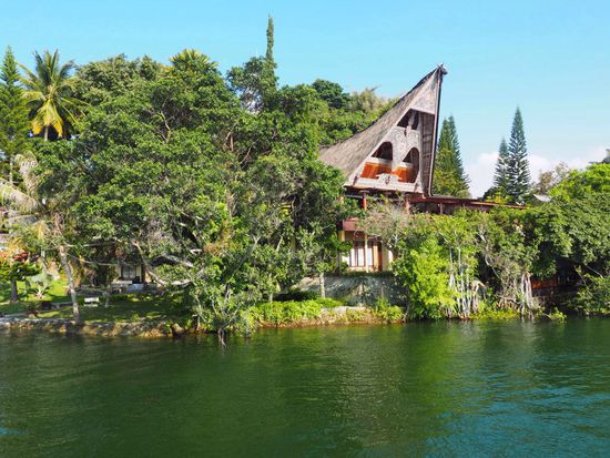 Typisches Batak-Haus am See mit üppiger Vegetation