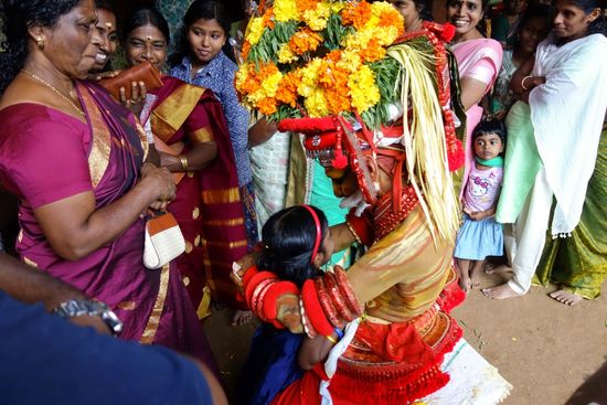 der "Gott" Mutthapan segnet ein Kind.
Am Ende dieser Vorführung bildeten sich Warteschlangen zu den beiden Tänzern, viele geben eine kleine Spende, jeder bekommt einen Segen oder wird mit ein paar Worten bedacht. Ich stellte mich auch in die Warteschlange