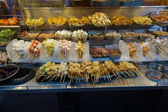 Solche Stände sah ich besonders auf Bukit Bintang. Eine Gegend mit Hochhäusern und den eher besseren Hotels. Man wählt sich einige dieser Spieße aus, die werden dann eine Zeitlang in eine kochende Brühe gesteckt. Das geht relativ schnell.