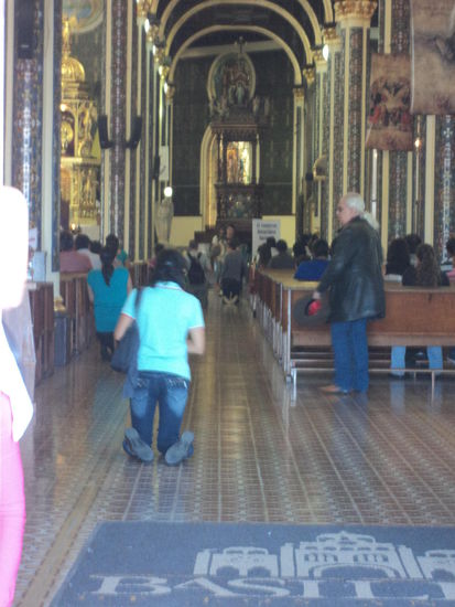 Menschen bewegen sich kniend vom Eingang der Basilika Richtung Altar
