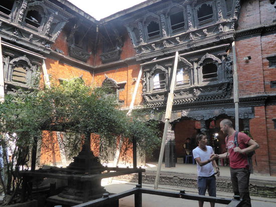 Kumari Chowk... hier lebt ein junges Mädchen, die Kumari, die als Verkörperung einer Göttin verhert wird. Die wenige Male, wo sie das Tempel verlässt, darf sie nicht den Boden berühren und wird deshalb getragen. Wenn Sie aber ihre erste Menstruation bekommt, wird sie ausgetauscht!  Sie erhält dann eine Rente vom Staat weil kein Mann sie heiraten will  
Der junge Mann auf dem Foto ist angeblich ein Reiseführer. Allerdings erzählt er uns nur Geschichten über Alkohol Bridge und Hippie Road... Passt!