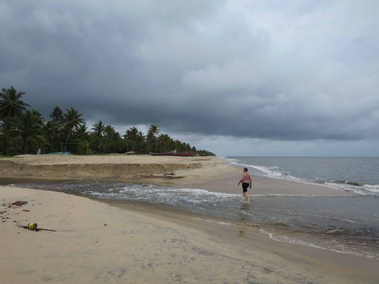 Ein Flußlauf der Backwaters hat die Sandbarriere durchbrochen und spült braunes Wasser ins Meer