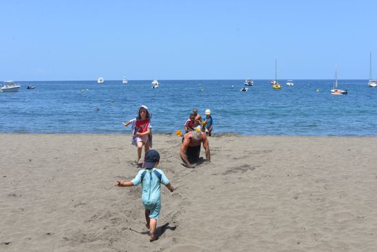 Superopa baut eine Straße, damit die Kinder nicht auf dem heißen Sand laufen müssen