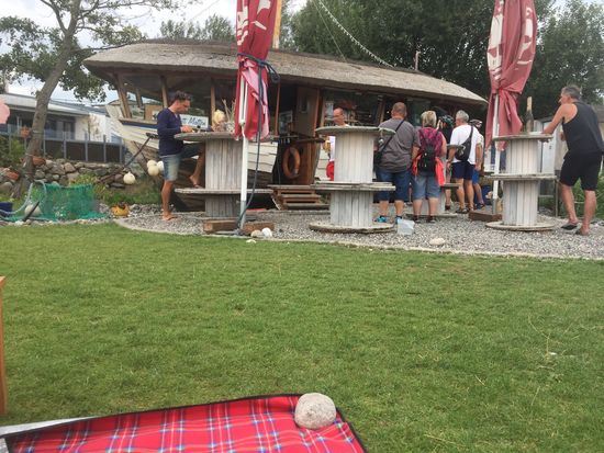 Fischbude am Hafen mit Picknickdecke und schwellendem Rasen