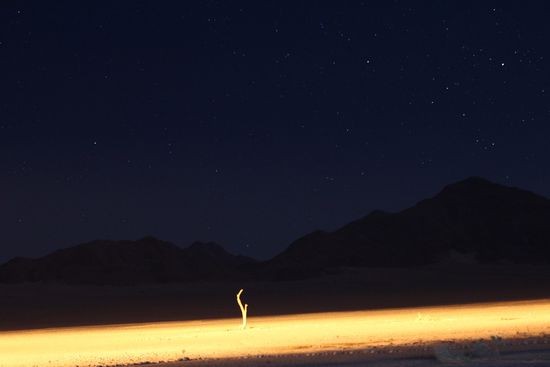 Beleuchtetes Wasserloch der Mirage Lodge vor Bergen unterm Nachthimmel...(Tiere hatten gerade keinen Durst )