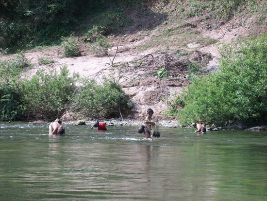 Kinder Fischen mit Netzen und sammeln Muscheln im Fluss
