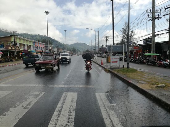 Was ist schlimmer, das autoähnliche Gefährt links oder der Regenschutz rechts. Ist auch schwer, wenn man auch noch das Getränk am Lenker hat.