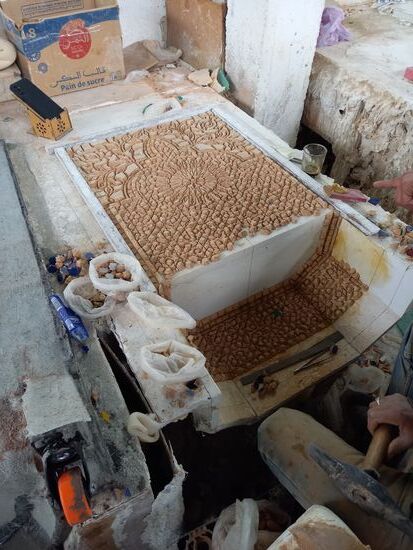 Hier wird ein Brunnen Steinchen für Steinchen zusammengesetzt.