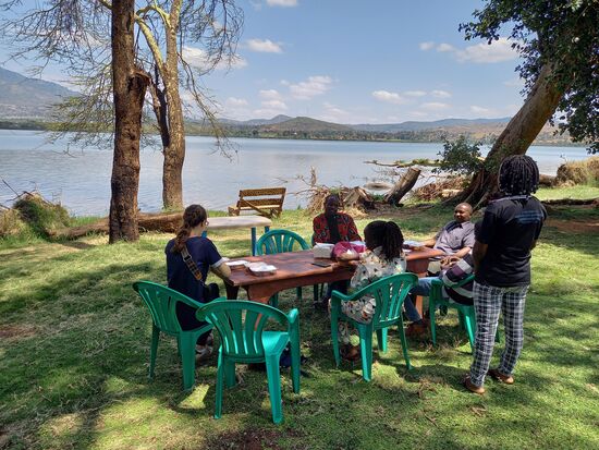 Mittagessen im Schatten riesiger Bäume. Es gibt lecker Samosa und Obst.