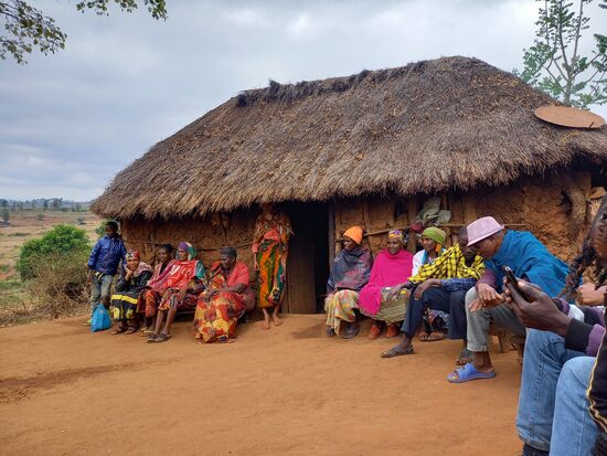Als wir ankommen werden wir bereits erwartet. Vor der Hütte sitzen die Frauen, die Männer sitzen im Halbkreis um uns herum.