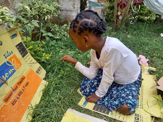 Esther nutzt eine Pappe um lesen zu üben.