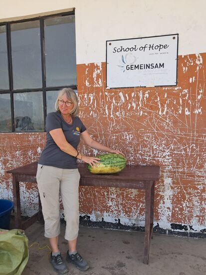 Nun werden die Melonen zerteilt. Wir erinnern uns an die ersten Besuche hier im Massai Gebiet in der "Schule" unter freiem Himmel. Da gab es nix. Mit einem Taschenmesser haben wir die Melonen auf einem Plastik Sack zerschnitten. Es gab auch keine Teller oder Tassen. Dafür gab es viele hungrige Frauen und Kinder!
