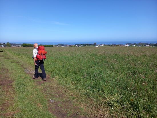 Entlang hügeliger Wiesen und den Blick bis zum Meer geht es lockeren Schrittes weiter.