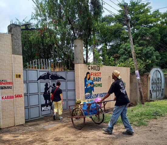Der junge Mann schiebt den Karren zum Baby Haus und verdient sich damit ein paar Schillinge.