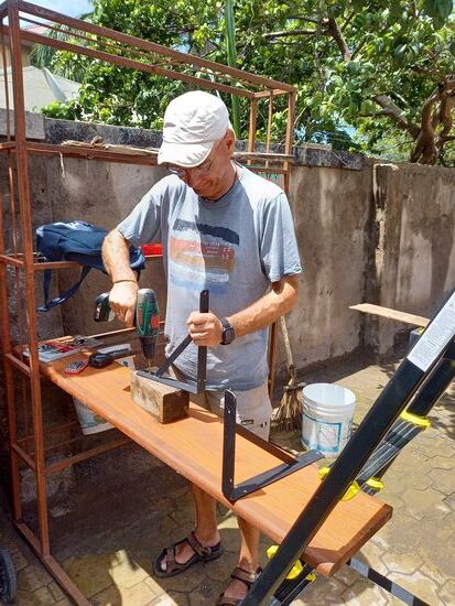 Das Regal in der Vorratskammer war zusammen gebrochen.  Nun werden solide Haken montiert. Matthias hat sie bei Vumilia anfertigen lassen. Allerdings ohne Bohrungen. Das macht Matthias nun selbst.