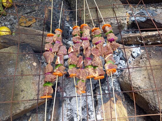 Über dem offenen Feuer brutzeln lecker Fleisch Spieße.