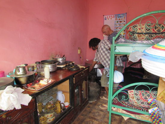 Hier ist die Küche auch gleichzeitig Schlafraum für vier Kinder. Im letzten Jahr lag hier eine Matraze am Boden, ohne Kissen und Decken. Dank vieler Spenden hat sich die Situation verbessert. Im Nebenzimmer steht ein weiteres Etagenbett. Der Raum ist jedoch so winzig, das es unmöglich ist ein Foto zu machen.
Happy erklärt Matthias wie hier Injera bereitet wird.