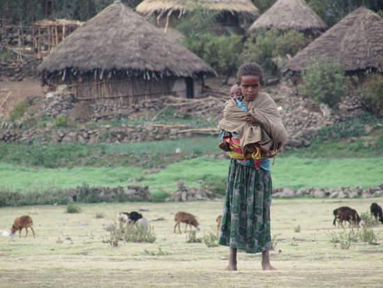 Ein kleines Mädchen, das nicht nur das Vieh hütet sondern auch noch ein kleines Geschwisterkind dabei hat.