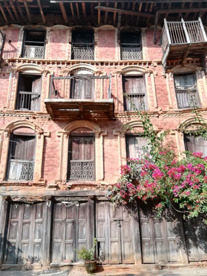 Wie ein Haus das die Bauweise der Newari zeigt, roter Ziegelstein in Verbindung mit aufwendigen Holzarbeiten.