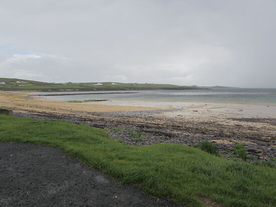 Ein goldgelber Strand und nur wenige Häuser im Hintergrund.