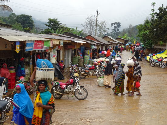 Der Regen hat die Straßen in schlammige Pisten verwandelt. Die Einheimischen trotzen dem Wetter und einige sind sogar barfuß unterwegs.