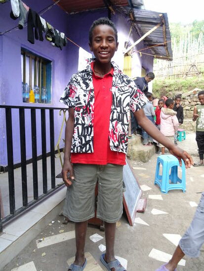 Aber auch viele andere Kinder freuen sich riesig. Im Hintergrund kann man sehen, wie die Mädchen und Jungen anstehen um etwas zu bekommen.