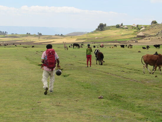 Über die weite Ebene geht es zu der Familie, die ich bereits kenne. Happy dribbelt derweil mit den Bällen, die wir der Schule bringen wollen.