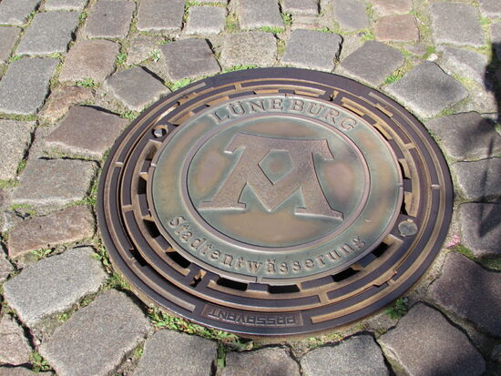 Anhand des Gullideckel erklärt uns Anne das Lüneburg einst durch drei Siedlungsgebiete zusammen gewachsen ist - Monz, Ponz und Vonz.
Monz steht für Berg, Ponz für die Brücke die über die Ilmenau führt und Vonz für die Quelle.