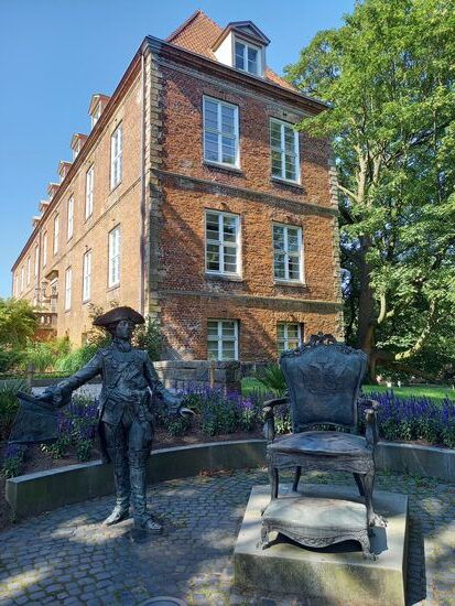 Treffpunkt ist die Skulptur des Zaren Peter III im Prinzengarten. Das rote Backsteingebäude beherbergt eine Bibliothek.