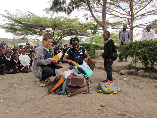 Während sich die Fußballer umziehen,  verteilen Anita und Psteen die Rucksäcke und Hefte.