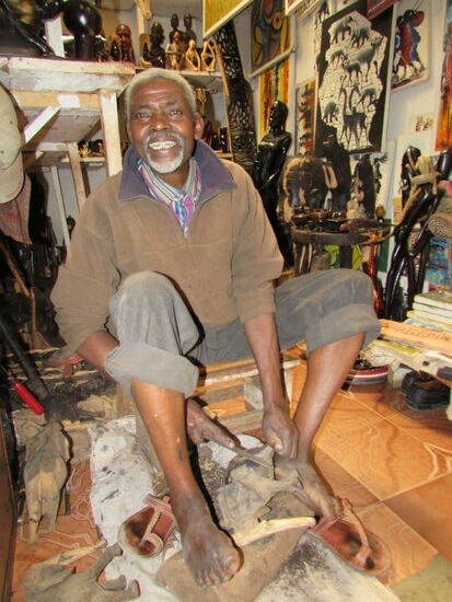 Seine Fröhlichkeit steckt an - er bietet Holzschnitzereien an.