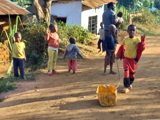 Diese Kinder haben Spaß  - in dem halbierten gelben Kanister wird stets eines der Kinder hinterher gezogen  
