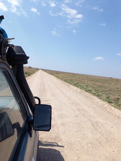 Die Schotterpiste geht gefühlt nur geradeaus  dem Horizont entgegen. Rechts und links der Piste Gras Steppe so weit das Auge reicht.