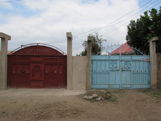 Einige Grundstücke sind von einer hohen Mauer umgeben und ein großes Tor aus Metall ermöglicht die Einfahrt.