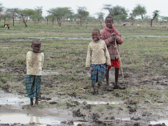 Einige der Kinder eilen neugierig herbei. Ihnen scheint der Matsch nichts aus zu machen..