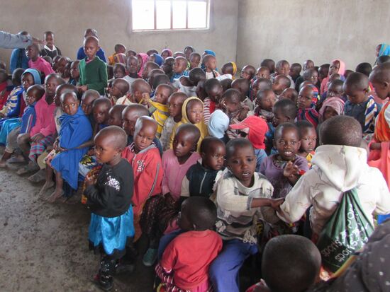 Mit ein paar Brettern wurden Bänke improvisiert. Die Kinder haben Stunden auf uns gewartet und haben daher in der Wartezeit bereits eine Tasse Porridge erhalten.
